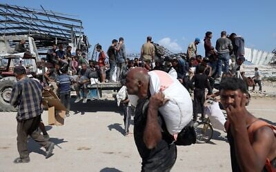 Des Palestiniens transportent des sacs alors qu'ils reviennent d'un point de distribution de nourriture géré par la Fondation humanitaire de Gaza, soutenue par les États-Unis et Israël, près du corridor de Netzarim, dans le centre de la bande de Gaza, le 3 août 2025. (Crédit : Eyad BABA / AFP) Des Palestiniens transportent des sacs alors qu'ils reviennent d'un point de distribution de nourriture géré par la Fondation humanitaire de Gaza, soutenue par les États-Unis et Israël, près du corridor de Netzarim, dans le centre de la bande de Gaza, le 3 août 2025. (Crédit : Eyad BABA / AFP)