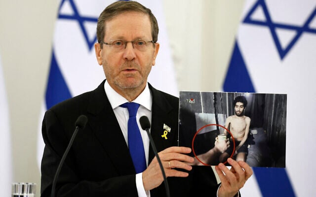 Le président Isaac Herzog tenant une photo prise à partir d'une capture d'écran d'une vidéo montrant l'otage israélien Evyatar David, lors d'une conférence de presse avec le président lituanien, au palais présidentiel de Vilnius, en Lituanie, le 4 août 2025. (Crédit : Petras Malukas/AFP)