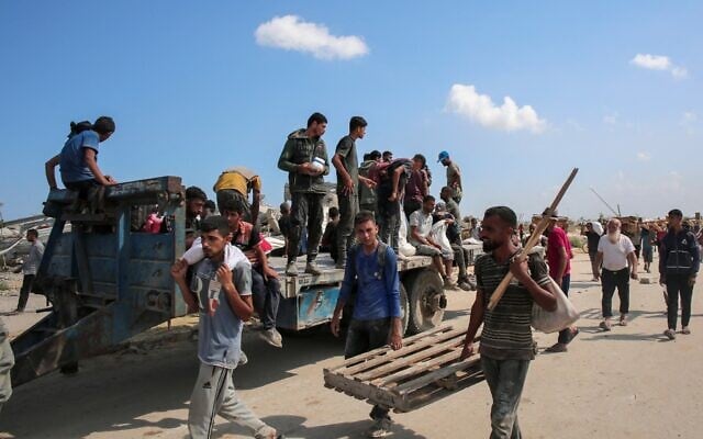 Des Gazaouis déplacés sur une remorquechargée de sacs d'aide humanitaire distribués par la Fondation humanitaire de Gaza (GHF), soutenue par les États-Unis et Israël, dans le « corridor de Netzarim », dans le centre de la bande de Gaza, le 4 août 2025. (Crédit : AFP)