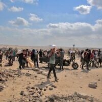Des Gazaouis déplacés transportant des sacs d'aide humanitaire qu'ils ont reçus dans un centre de distribution géré par la Fondation humanitaire de Gaza (GHF), soutenue par les États-Unis et Israël, dans le centre de la bande de Gaza, le 4 août 2025. (Crédits : AFP)