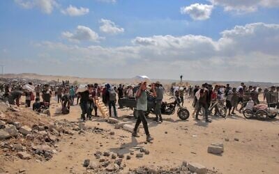 Des Gazaouis déplacés transportant des sacs d'aide humanitaire qu'ils ont reçus dans un centre de distribution géré par la Fondation humanitaire de Gaza (GHF), soutenue par les États-Unis et Israël, dans le centre de la bande de Gaza, le 4 août 2025. (Crédits : AFP)