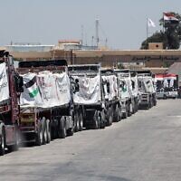 Des camions chargés d'aide humanitaire attendent l'autorisation de passer le poste-frontière de Rafah, du côté égyptien de la bande de Gaza, pour entrer en territoire palestinien, le 6 août 2025. (Crédit : AFP)