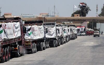 Des camions chargés d'aide humanitaire attendent l'autorisation de passer le poste-frontière de Rafah, du côté égyptien de la bande de Gaza, pour entrer en territoire palestinien, le 6 août 2025. (Crédit : AFP)