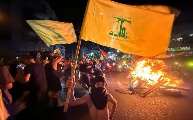 Des partisans du groupe terroriste chiite libanais du Hezbollah bloquant les rues avec des pneus en feu alors qu'ils se rassemblent en voitures et en motos pour protester contre le soutien du gouvernement à un plan visant à le désarmer, dans la banlieue sud de Beyrouth, très tôt 8 août 2025. (Crédit : Ibrahim Amro/AFP)