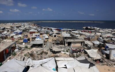 Des tentes servant d'abris temporaires aux Gazaouis déplacés installées autour de bâtiments endommagés par la guerre, le long de la plage de Gaza-City, le 8 août 2025. (Crédit : Bashar Taleb/AFP)