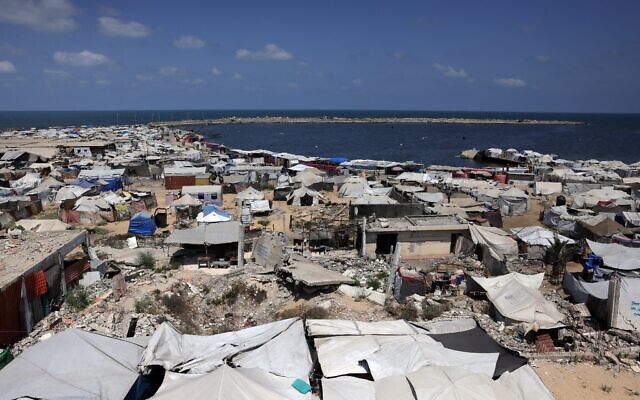 Des tentes servant d'abris temporaires aux Gazaouis déplacés installées autour de bâtiments endommagés par la guerre, le long de la plage de Gaza-City, le 8 août 2025. (Crédit : Bashar Taleb/AFP)
