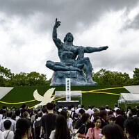 Des personnes se tenant devant la statue de la Paix après la cérémonie commémorative annuelle en hommage aux victimes, au Parc de la Paix de Nagasaki, le 9 août 2025, pour marquer le 80ᵉ anniversaire du bombardement atomique pendant la Seconde Guerre mondiale. (Crédit : Philip Fong/AFP)