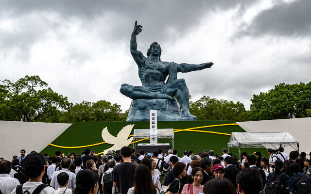 Des personnes se tenant devant la statue de la Paix après la cérémonie commémorative annuelle en hommage aux victimes, au Parc de la Paix de Nagasaki, le 9 août 2025, pour marquer le 80ᵉ anniversaire du bombardement atomique pendant la Seconde Guerre mondiale. (Crédit : Philip Fong/AFP)