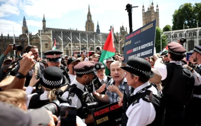 Des policiers discutent avec un manifestant pendant une manifestation pour soutenir le groupe interdit Palestine Action, sur Parliament Square, dans le centre de Londres, le 9 août 2025. (Crédit : HENRY NICHOLLS / AFP)