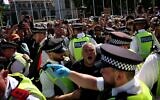 Des policiers discutent avec un manifestant pendant une manifestation pour soutenir le groupe interdit Palestine Action, sur Parliament Square, dans le centre de Londres, le 9 août 2025. (Crédit : HENRY NICHOLLS / AFP)