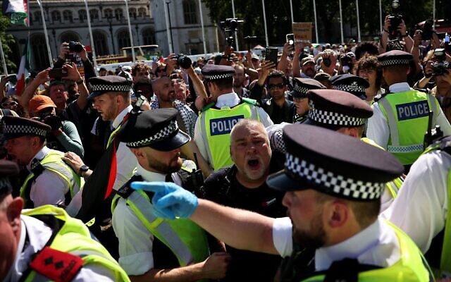 Des policiers discutent avec un manifestant pendant une manifestation pour soutenir le groupe interdit Palestine Action, sur Parliament Square, dans le centre de Londres, le 9 août 2025. (Crédit : HENRY NICHOLLS / AFP)