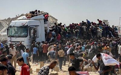 Des Gazaouis déplacés transportant des colis alimentaires après avoir pillé des camions transportant de l'aide humanitaire, à Khan Younès, dans le sud de la bande de Gaza, le 9 août 2025. (Crédit : AFP)