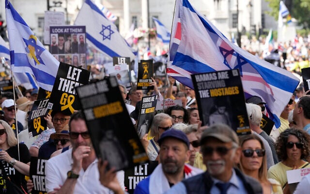 Des personnes brandissent des drapeaux et des pancartes lors d'une "Marche nationale pour les otages" organisée par Stop the Hate UK, dans le centre de Londres, le 10 août 2025. (Crédit : CARLOS JASSO / AFP)
