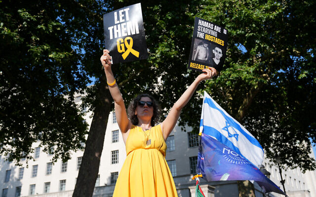 Une personne brandit des drapeaux et des pancartes lors d'une "Marche nationale pour les otages" organisée par Stop the Hate UK, dans le centre de Londres, le 10 août 2025. (Crédit : CARLOS JASSO / AFP) Une personne brandit des drapeaux et des pancartes lors d'une "Marche nationale pour les otages" organisée par Stop the Hate UK, dans le centre de Londres, le 10 août 2025. (Crédit : CARLOS JASSO / AFP)