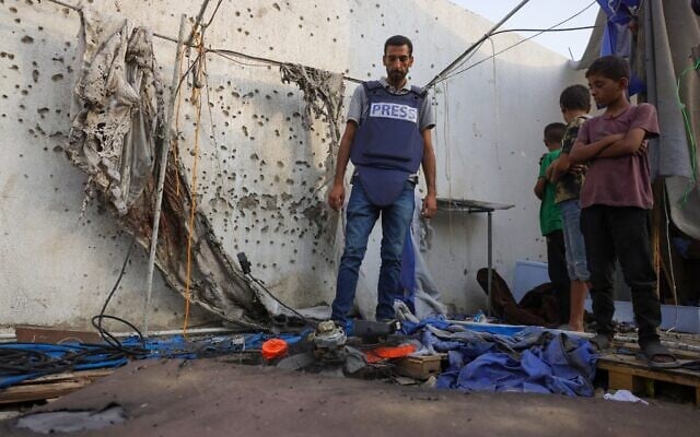 Des enfants palestiniens et un journaliste examinent la tente détruite d’Al Jazeera, à la suite d’une frappe nocturne de l’armée israélienne, à l’hôpital Al-Shifa de Gaza, le 11 août 2025. (Crédit : Bashar Taleb/AFP)