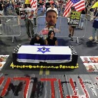 Enav Zangauker (à droite), mère de l’otage israélien Matan Zangauker, assise avec une amie près d’un faux cercueil, lors d’une manifestation contre le gouvernement réclamant des mesures pour obtenir la libération des otages israéliens retenus depuis le pogrom du Hamas du 7 octobre 2023, devant le ministère de la Défense, à Tel-Aviv, le 12 août 2025. (Crédit : Jack Guez / AFP)