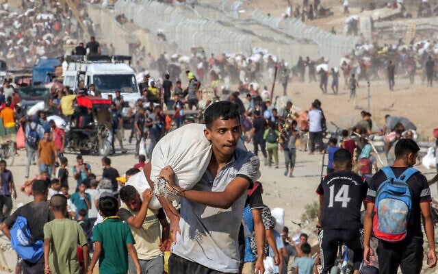 Un Gazaoui marchant avec un sacs d'aide humanitaire qui lui a été remis dans un centre de distribution géré par la Fondation humanitaire de Gaza (GHF), soutenue par les États-Unis et Israël, dans le centre de la bande de Gaza, le 22 août 2025. (Crédit : Eyad Baba/AFP) Un Gazaoui marchant avec un sacs d'aide humanitaire qui lui a été remis dans un centre de distribution géré par la Fondation humanitaire de Gaza (GHF), soutenue par les États-Unis et Israël, dans le centre de la bande de Gaza, le 22 août 2025. (Crédit : Eyad Baba/AFP)