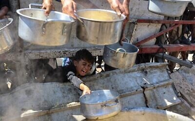Un garçon palestinien tend une casserole vide devant le stand d'une organisation caritativedans l'espoir d'avoir du riz cuit, dans la ville de Gaza, le 23 août 2025. (Omar AL-QATTAA / AFP) Un garçon palestinien tend une casserole vide devant le stand d'une organisation caritativedans l'espoir d'avoir du riz cuit, dans la ville de Gaza, le 23 août 2025. (Omar AL-QATTAA / AFP)