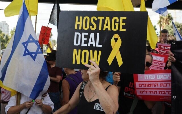 Des manifestants brandissant des pancartes et des drapeaux d'Israël lors d'un rassemblement, à Tel Aviv, le 26 août 2025. (Crédit : Jack Guez/AFP)