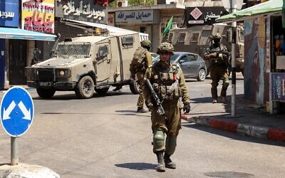 Des soldats israéliens mènent un raid dans la ville de Ramallah, en Cisjordanie, le 26 août 2025. (Crédit : Zain JAAFAR / AFP)