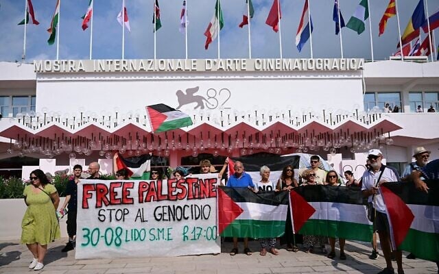 Un groupe de militants anti-Israël derrière une banderole sur laquelle on peut lire « Free Palestine - Stop Genocide » avant la cérémonie d'ouverture du 82ᵉ Festival du film de Venise, au Lido, à Venise, le 27 août 2025. (Crédit : Tiziana Fabi/AFP) Un groupe de militants anti-Israël derrière une banderole sur laquelle on peut lire « Free Palestine - Stop Genocide » avant la cérémonie d'ouverture du 82ᵉ Festival du film de Venise, au Lido, à Venise, le 27 août 2025. (Crédit : Tiziana Fabi/AFP)