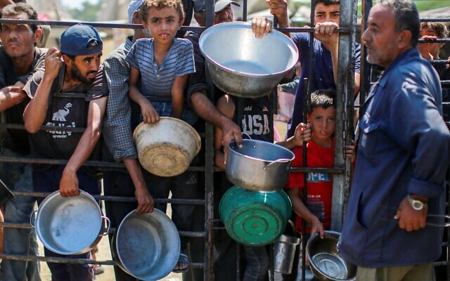 Des Gazaouis attendant pour recevoir du riz dans une cuisine communautaire qui distribue gratuitement de la nourriture dans l'ouest de Gaza-City, le 28 août 2025. (Crédit : Bashar Taleb/AFP) Des Gazaouis attendant pour recevoir du riz dans une cuisine communautaire qui distribue gratuitement de la nourriture dans l'ouest de Gaza-City, le 28 août 2025. (Crédit : Bashar Taleb/AFP)