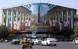 Des Iraniens passant devant un panneau d'affichage montrant des photos de scientifiques nucléaires, de centrifugeuses et une phrase en farsi : "La science est le pouvoir" sur la place Enqelab à Téhéran, le 29 août 2025 (Crédit : AFP)