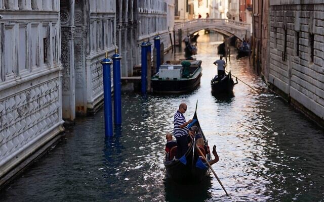 Des gondoliers emmènent des touristes au Ponte dei Sospiri (Pont des Soupirs), à Venise, en Italie, le 17 juin 2021. (Crédit : AP Photo/Luca Bruno)
