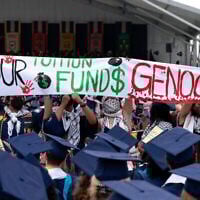 Des étudiants de l'Université George Washington portent une pancarte lors d'une manifestation anti-Israël alors que la présidente de l'Université George Washington, Ellen Granberg, prend la parole lors d'une cérémonie de remise des diplômes à Washington, le 19 mai 2024. (Crédit : AP Photo/Jose Luis Magana)