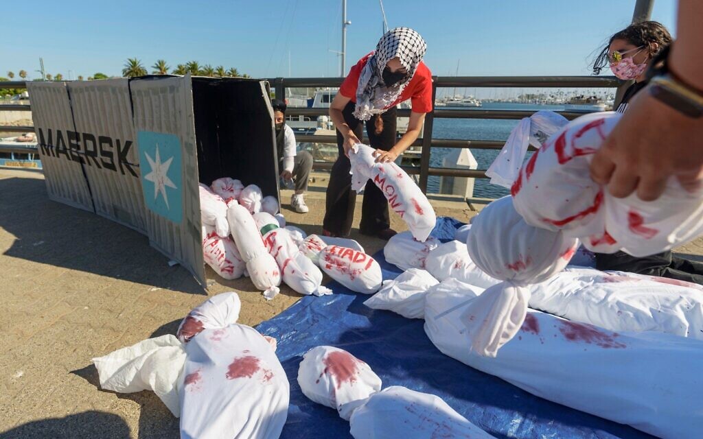 Des membres du Mouvement de la jeunesse palestinienne sortent des effigies d'un conteneur maritime lors d'une manifestation contre le géant du transport maritime et de la logistique Maersk pour ses relations commerciales avec Israël, le 28 août 2024, au port de Los Angeles. Illustration (Crédit : Damian Dovarganes/AP)