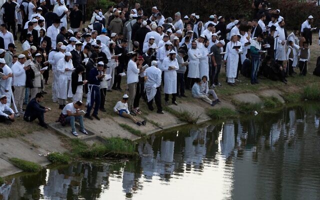 Des juifs orthodoxes prient près du lac, devant la tombe du rabbin Nachman, arrière-petit-fils du fondateur du mouvement hassidique, dans la ville d'Ouman, en Ukraine, le 3 octobre 2024. (Crédit : AP Photo/Efrem Lukatsky)