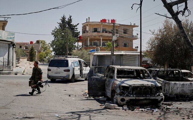 Illustration : Un milicien druze armé d'une mitrailleuse passant devant une voiture incendiée, à la suite d'affrontements religieux dans la ville à majorité druze de Soueïda, en Syrie, le 25 juillet 2025. (Crédit : Omar Sanadiki/AP Photo)