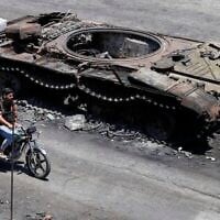 Photo d'illustration : Des miliciens druzes passent à moto devant un véhicule militaire détruit lors d'affrontements religieux la semaine dernière dans la ville à majorité druze de Soueïda, en Syrie, le 25 juillet 2025. (Crédit : AP Photo/Omar Sanadiki)