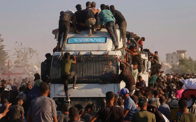 Des Gazaouis à bord d'un camion chargé de vivres et d'aide humanitaire circulant dans le corridor de Morag, près de Rafah, dans le sud de la bande de Gaza, le 4 août 2025. (Crédit : Mariam Dagga/AP)
