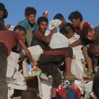 Des Palestiniens luttent pour obtenir de la nourriture et de l'aide humanitaire à l'arrière d'un camion en train de se déplacer le long du corridor de Morag, près de Rafah, dans le sud de la bande de Gaza, le 4 août 2025. (Crédit : AP Photo/ Mariam Dagga)
