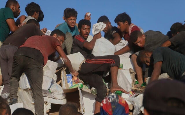Des Palestiniens luttent pour obtenir de la nourriture et de l'aide humanitaire à l'arrière d'un camion en train de se déplacer le long du corridor de Morag, près de Rafah, dans le sud de la bande de Gaza, le 4 août 2025. (Crédit : AP Photo/ Mariam Dagga)