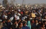 Des Palestiniens transportent des colis alimentaires provenant d'un convoi humanitaire ayant emprunté le corridor de Morag près de Rafah, dans le sud de la bande de Gaza, le 4 août 2025. (Crédit : AP Photo/Mariam Dagga)