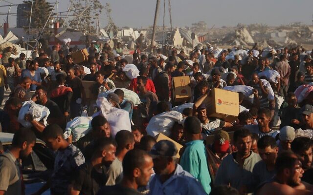 Des Palestiniens transportent des colis alimentaires provenant d'un convoi humanitaire ayant emprunté le corridor de Morag près de Rafah, dans le sud de la bande de Gaza, le 4 août 2025. (Crédit : AP Photo/Mariam Dagga) Des Palestiniens transportent des colis alimentaires provenant d'un convoi humanitaire ayant emprunté le corridor de Morag près de Rafah, dans le sud de la bande de Gaza, le 4 août 2025. (Crédit : AP Photo/Mariam Dagga)