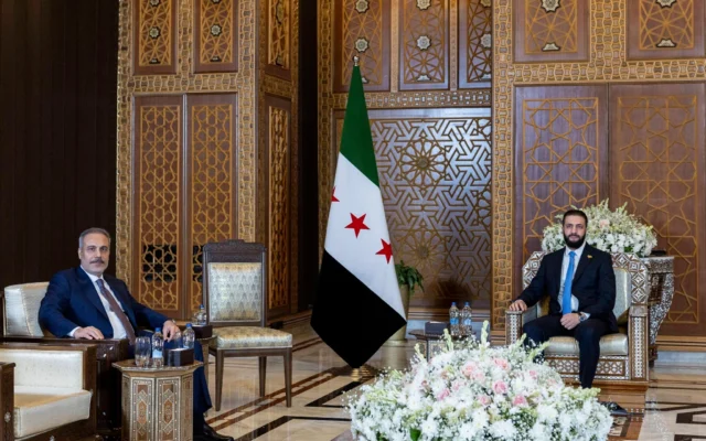 Lle ministre turc des Affaires étrangères Hakan Fidan, à gauche, est assis aux côtés du président par intérim syrien Ahmad Al-Sharaa, lors de leur rencontre à Damas, en Syrie, le 7 août 2025. (Crédit : Ministère turc des Affaires étrangères via AP)