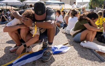 Des personnes s'assoient par terre et se couvrent la tête alors que des sirènes annoncent l'arrivée d'un missile tiré depuis le Yémen lors d'une manifestation exigeant la libération immédiate des otages détenus par le Hamas, à Tel-Aviv, le 17 août 2025. (Crédit : AP Photo/Maya Levin)