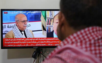 Un homme regarde la télévision qui diffuse des images d'Ahmed al-Rahawi, le Premier ministre du gouvernement houthi, tué lors des frappes israéliennes du 28 août, à Sanaa, au Yémen, le 30 août 2025. (Crédit : Osamah Abdulrahman/AP)