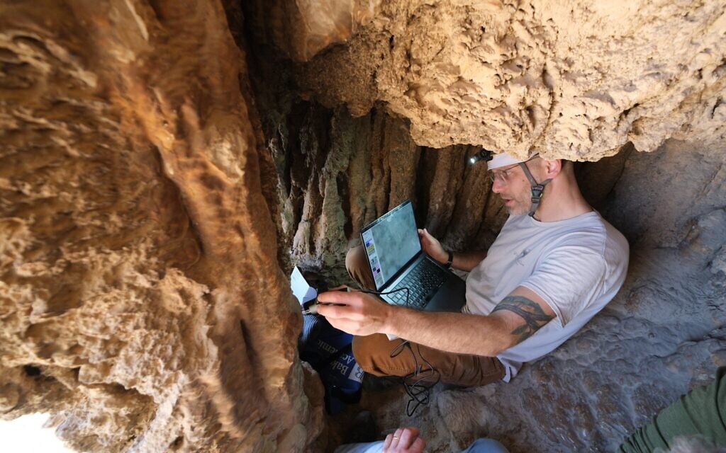 Le Dr Asaf Gayer, du département d'études sur la terre d'Israël et d'archéologie de l'université d'Ariel, examine une grotte près du parc national d'Ein Gedi, dans la région de la mer Morte, où se trouve une ancienne inscription en araméen, datant peut-être de la révolte de Bar Kochba, qui a été révélée au grand public en août 2025. (Crédit : Asaf Gayer)