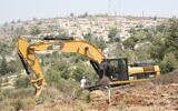 Un tracteur Caterpillar défrichant un terrain pour la construction de maisons israéliennes en Cisjordanie, en 2012. (Crédit : Oren Nahshon/Flash90)