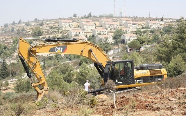 Un tracteur Caterpillar défrichant un terrain pour la construction de maisons israéliennes en Cisjordanie, en 2012. (Crédit : Oren Nahshon/Flash90)