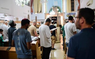 Des Juifs pratiquants rassemblés à la veille de Tisha Beav dans une synagogue de Tel Aviv pour la lecture annuelle du Livre des Lamentations, le 12 août 2024. (Crédit : Tomer Neuberg/Flash90)