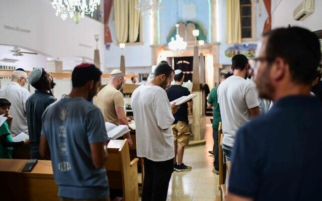 Des Juifs pratiquants rassemblés à la veille de Tisha Beav dans une synagogue de Tel Aviv pour la lecture annuelle du Livre des Lamentations, le 12 août 2024. (Crédit : Tomer Neuberg/Flash90)