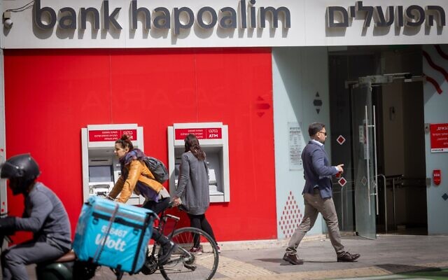 Illustration : Des passants devant une agence de la banque Hapoalim à Tel Aviv, le 25 mars 2025. (Crédit : Miriam Alster/FLASH90)