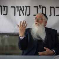 Le député Meir Porush devant une banderole sur laquelle on peut lire « Bureau du député Meir Porush », devant les locaux du ministère de la Justice, à Jérusalem, le 7 août 2025. (Chaim Goldberg/Flash90)