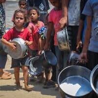 Des Palestiniens reçoivent des repas distribués par des bénévoles à Gaza-City, le 10 août 2025. (Crédit : Ali Hassan/Flash90)