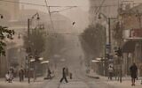 Des gens traversant les voies du tramway sur la rue Jaffa, à Jérusalem lors d'une journée estivale brumeuse, le 11 août 2025. (Crédit : Chaïm Goldberg/Flash90)